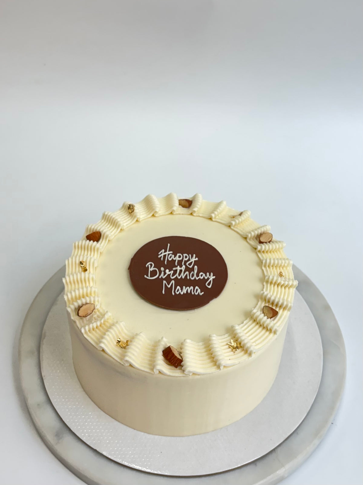 Vanilla Buttercream Praline Crunch Cake with piped buttercream border and chocolate birthday plaque
